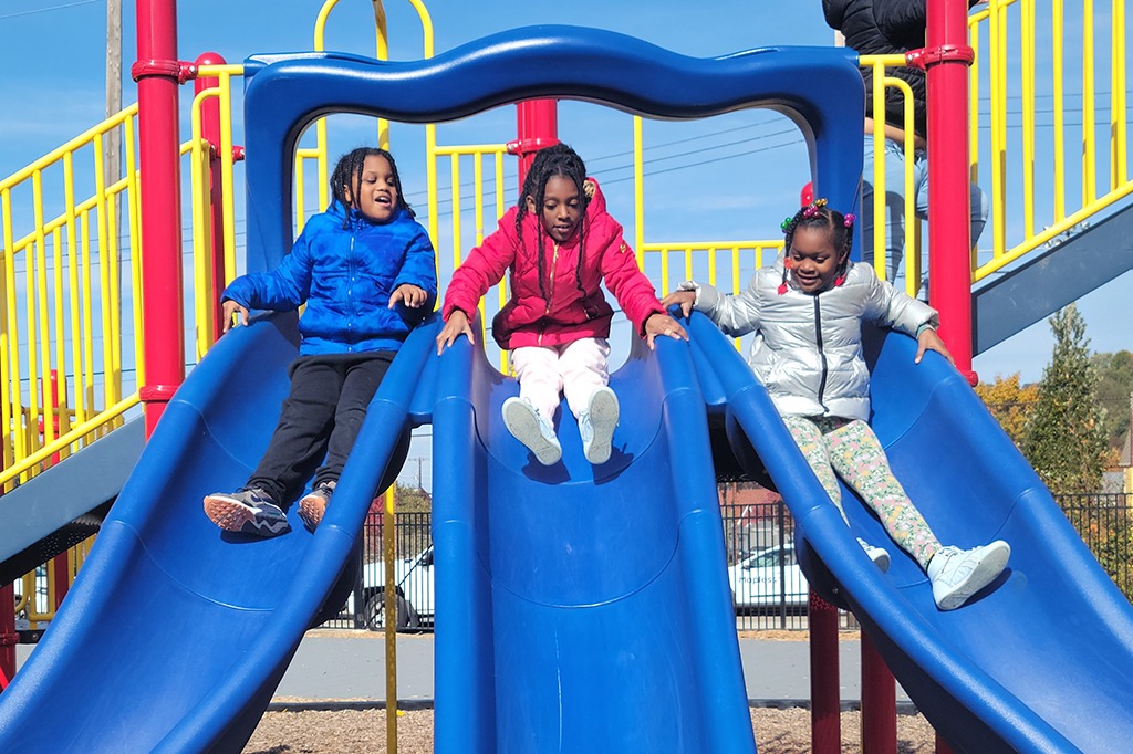 Three 2nd grade students go down a triple slide.