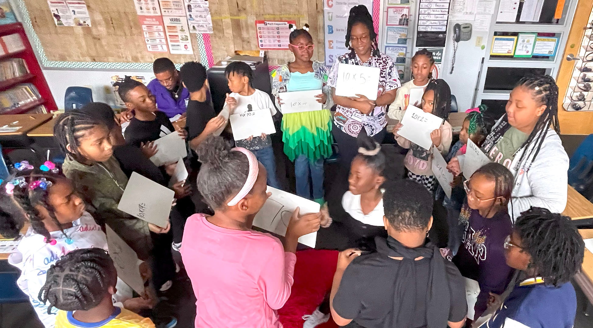 Several 3rd Grade students stand in a circle with a teacher.