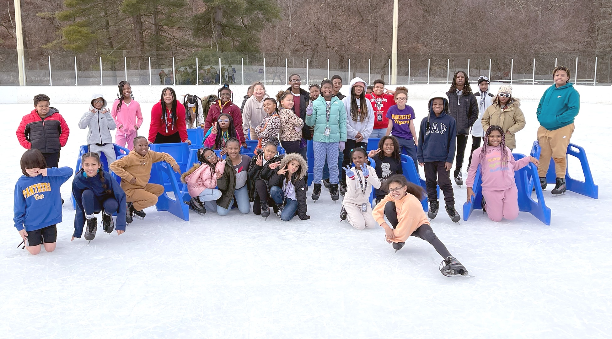 a large group of students pose for a group photo in the middle of an ice rink.