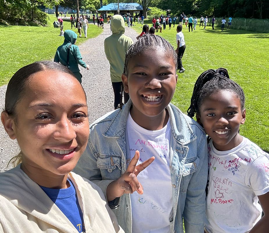 Two girls smile with a female teacher at Avalon Park.