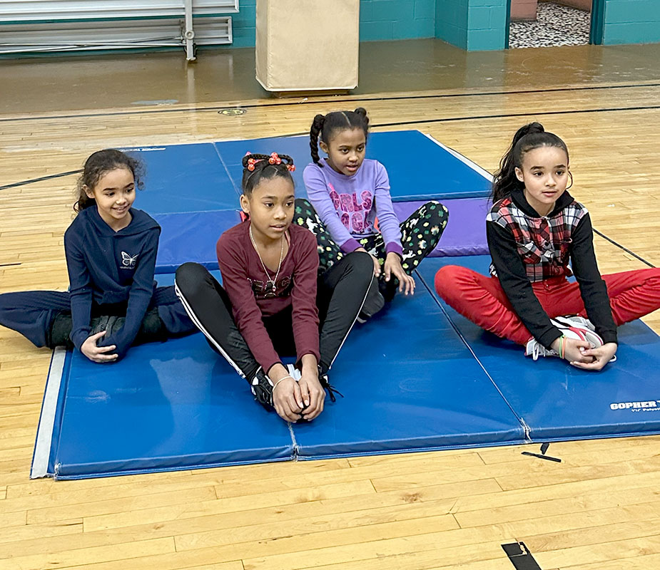 Four girls sitting on mats for yoga.