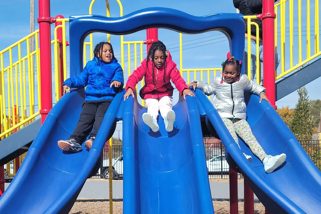 Three 2nd grade students go down a triple slide. Three 2nd grade students go down a triple slide.