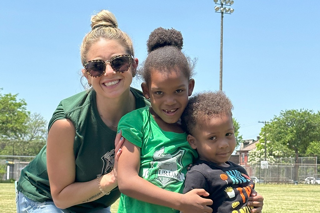 A teacher poses with two students. A teacher poses with two students.