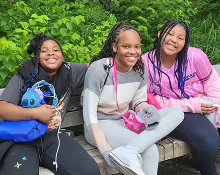 Three girls sitting on a park bench smiling. Three girls sitting on a park bench smiling.
