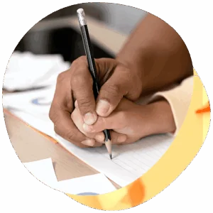 An adult hand guides an adolescent's hand as they write.