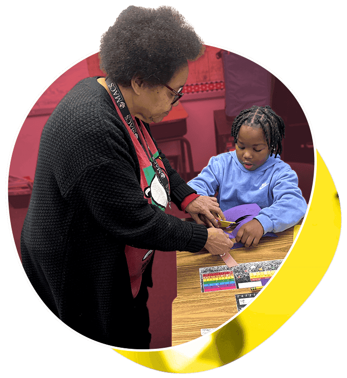 baldwin and student_750x750 A teacher works with a you student at his desk.